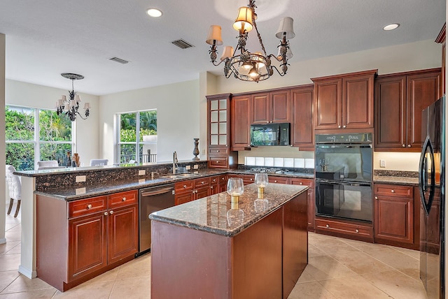 kitchen featuring black appliances, pendant lighting, a kitchen island, and an inviting chandelier