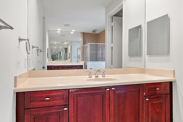 bathroom with vanity and a shower with door