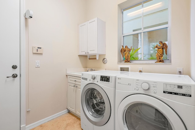 clothes washing area featuring cabinets, washing machine and dryer, and light tile patterned floors