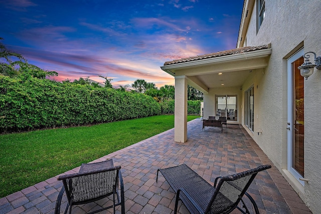 patio terrace at dusk with outdoor lounge area and a lawn