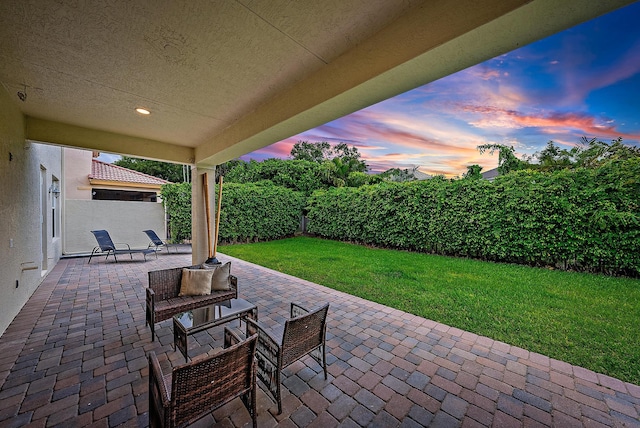 patio terrace at dusk featuring a yard