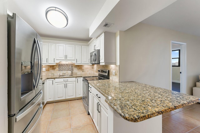 kitchen featuring kitchen peninsula, appliances with stainless steel finishes, tasteful backsplash, a breakfast bar, and white cabinetry