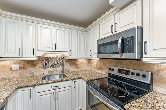 kitchen featuring stone counters, sink, decorative backsplash, white cabinetry, and stainless steel appliances