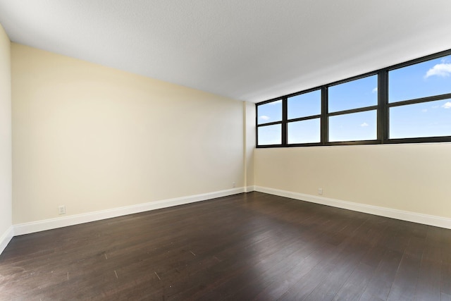 spare room with plenty of natural light and dark hardwood / wood-style flooring