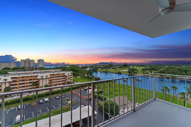 balcony at dusk with ceiling fan and a water view