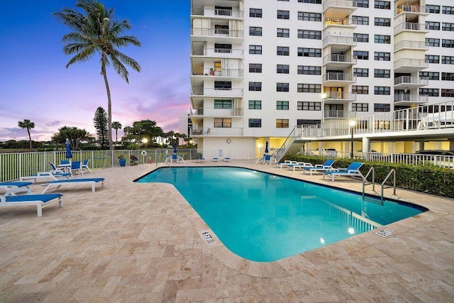 pool at dusk with a patio area