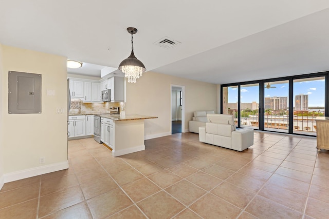 kitchen with electric panel, white cabinets, expansive windows, appliances with stainless steel finishes, and light stone counters