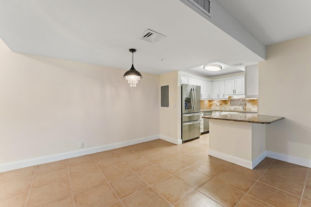 kitchen featuring white cabinetry, stainless steel appliances, kitchen peninsula, dark stone countertops, and light tile patterned flooring