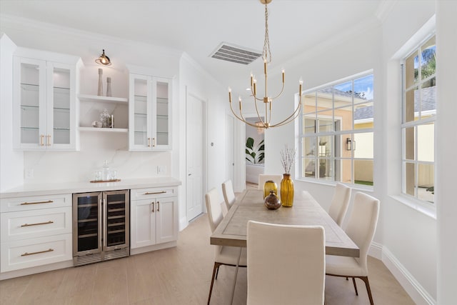 dining area with a chandelier, beverage cooler, and crown molding