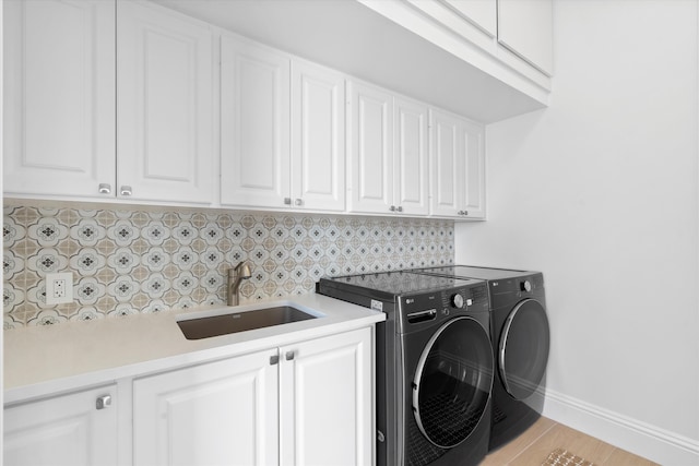 laundry room featuring cabinets, independent washer and dryer, and sink