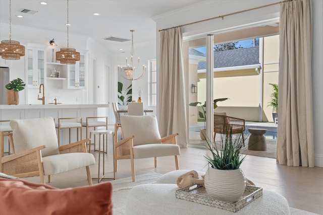 living area with crown molding, sink, and a chandelier