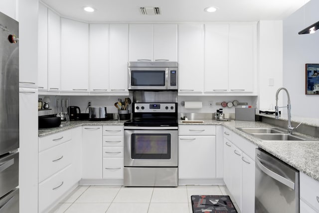 kitchen featuring light stone countertops, appliances with stainless steel finishes, sink, light tile patterned floors, and white cabinets