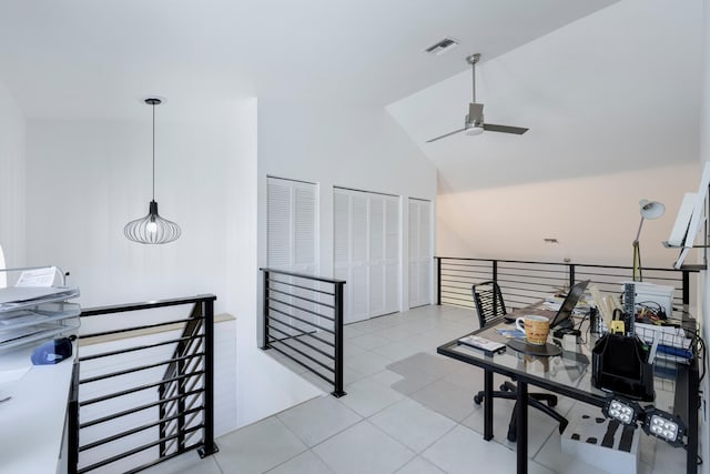 home office featuring ceiling fan, light tile patterned flooring, and vaulted ceiling