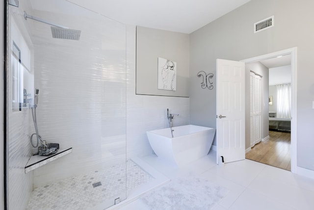 bathroom featuring tile patterned flooring, tile walls, and independent shower and bath