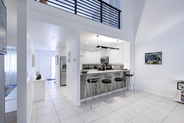 kitchen with stainless steel appliances, white cabinetry, a wealth of natural light, and light tile patterned flooring