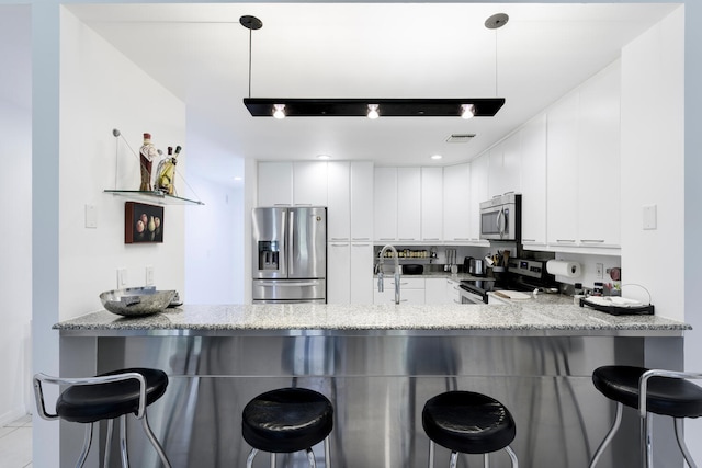 kitchen with a breakfast bar, kitchen peninsula, hanging light fixtures, and appliances with stainless steel finishes