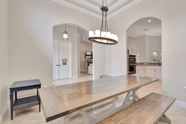 tiled dining space with a chandelier, crown molding, and sink