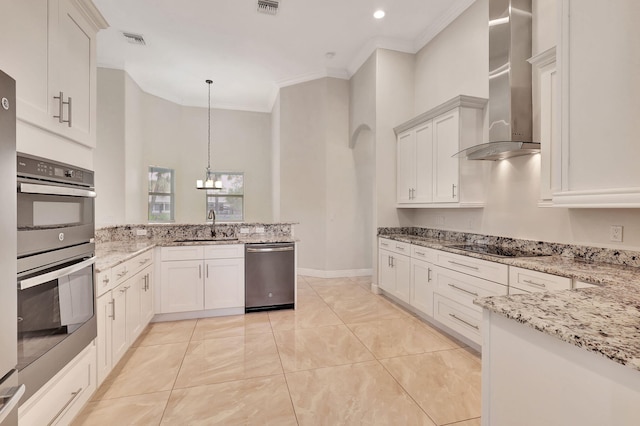 kitchen with appliances with stainless steel finishes, ornamental molding, wall chimney exhaust hood, white cabinets, and hanging light fixtures