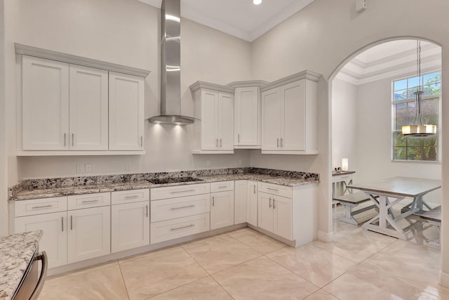 kitchen with black electric stovetop, wall chimney exhaust hood, light stone countertops, ornamental molding, and white cabinetry