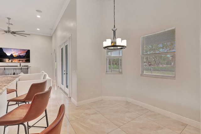 tiled dining space with crown molding, french doors, and ceiling fan with notable chandelier