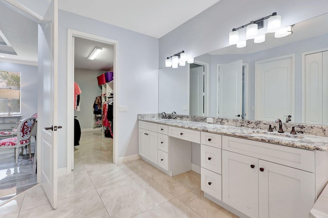 bathroom featuring double vanity, a spacious closet, a sink, and tile patterned floors