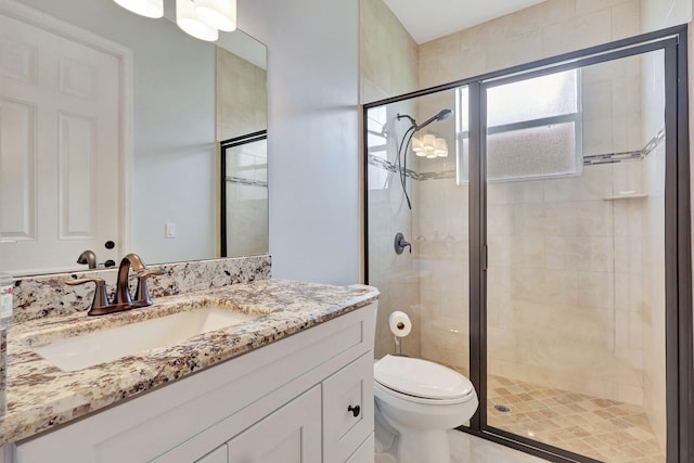 bathroom featuring vanity, toilet, and a shower with door