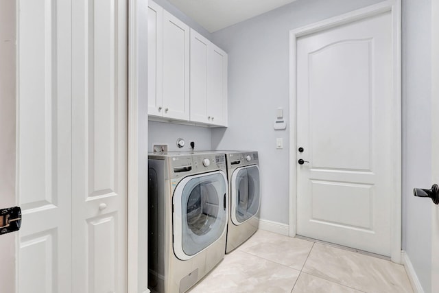 laundry area with cabinets, light tile patterned floors, and washing machine and clothes dryer