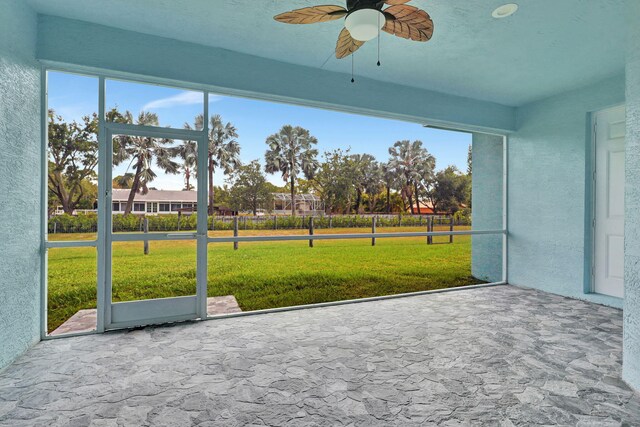 unfurnished sunroom featuring a ceiling fan