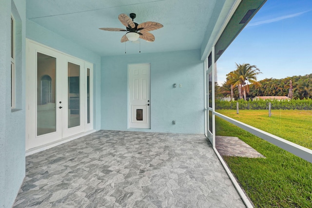 unfurnished sunroom featuring ceiling fan and french doors