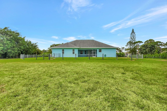 rear view of property featuring a yard and fence