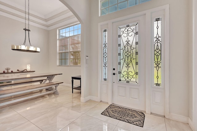 entryway featuring arched walkways, an inviting chandelier, baseboards, and crown molding