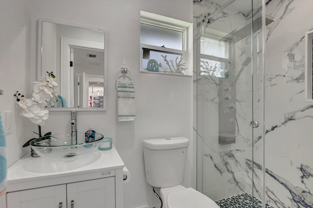 bathroom featuring vanity, a shower with shower door, and toilet