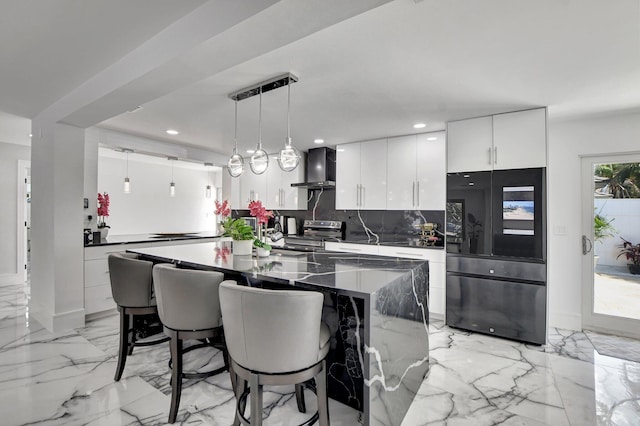 kitchen with wall chimney range hood, black fridge, stainless steel range with electric cooktop, pendant lighting, and white cabinets