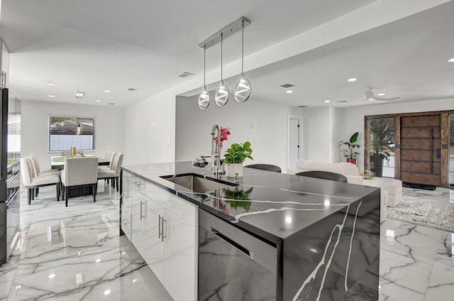 kitchen with ceiling fan, sink, a center island with sink, white cabinetry, and hanging light fixtures