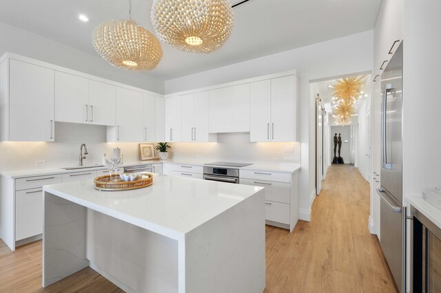 kitchen with sink, light hardwood / wood-style flooring, a center island, and stainless steel appliances