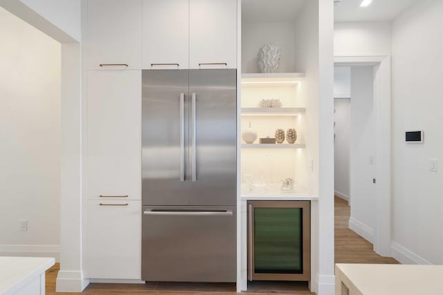 kitchen with light wood-type flooring, built in fridge, and white cabinets