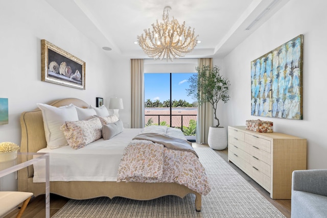 bedroom featuring a raised ceiling, hardwood / wood-style floors, and a chandelier