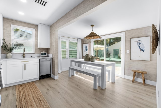 kitchen featuring dishwasher, sink, hanging light fixtures, light hardwood / wood-style floors, and white cabinets