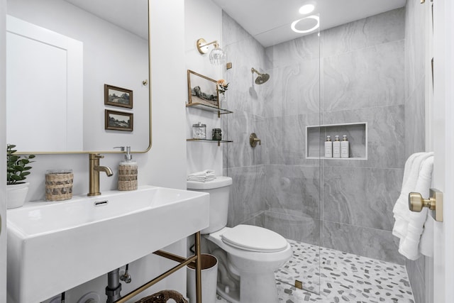 bathroom with a tile shower, sink, and toilet