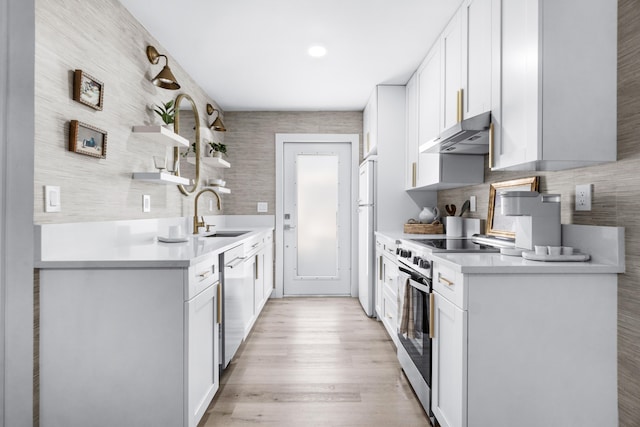 kitchen with sink, stainless steel appliances, white cabinetry, and range hood