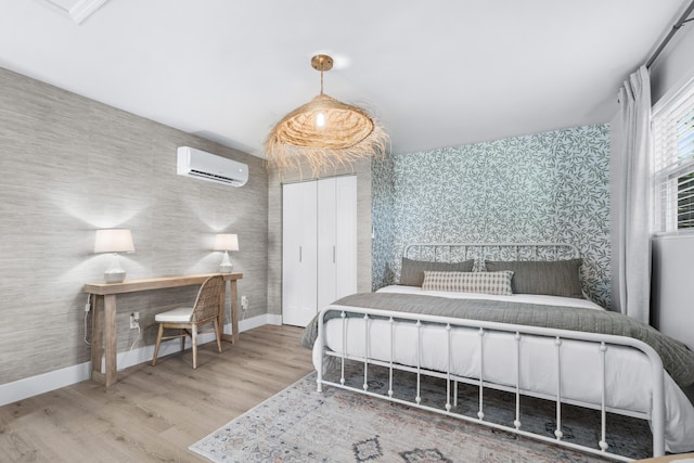 bedroom with a wall mounted air conditioner and hardwood / wood-style flooring