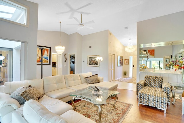 living area with high vaulted ceiling, visible vents, ceiling fan, and wood finished floors