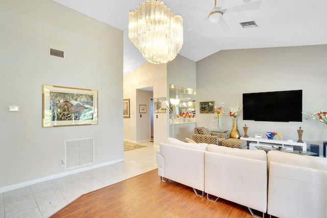 living room featuring ceiling fan with notable chandelier, vaulted ceiling, and light wood-type flooring