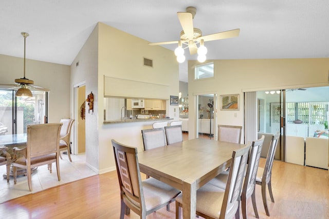 dining space featuring ceiling fan, sink, lofted ceiling, and light wood-type flooring