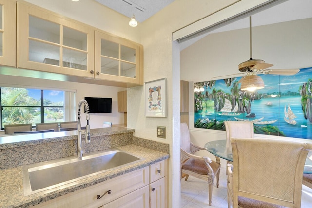 kitchen featuring ceiling fan, sink, hanging light fixtures, light stone counters, and light tile patterned floors