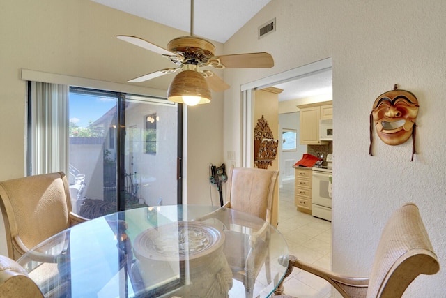 tiled dining space featuring ceiling fan and vaulted ceiling