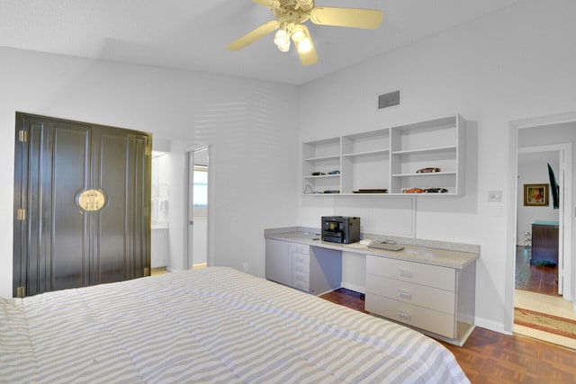 bedroom with ceiling fan, dark parquet flooring, and built in desk