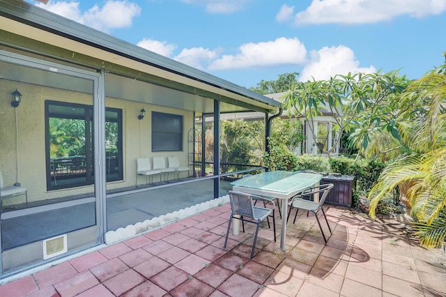 view of patio with outdoor dining space and a sunroom