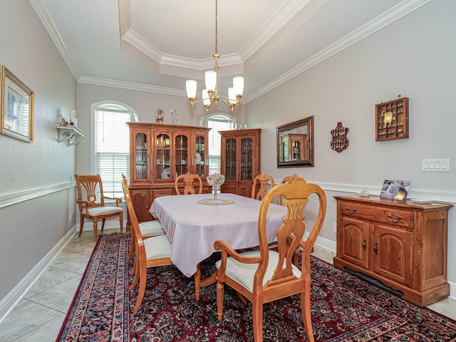 tiled dining space featuring an inviting chandelier, a tray ceiling, and crown molding