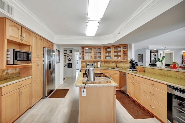 kitchen with beverage cooler, stainless steel appliances, a center island, kitchen peninsula, and ornamental molding